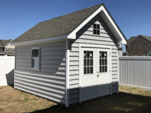 A modern gray vinyl siding storage shed with white trim and double doors, built by RMG Construction in Chesapeake, VA.