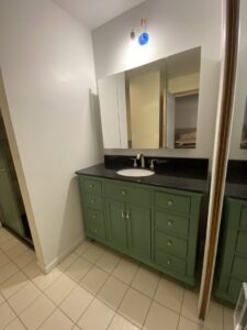 A newly installed green bathroom vanity with a black countertop, sink, and medicine cabinet by Coastal Home Improvements in Greenwood, DE.