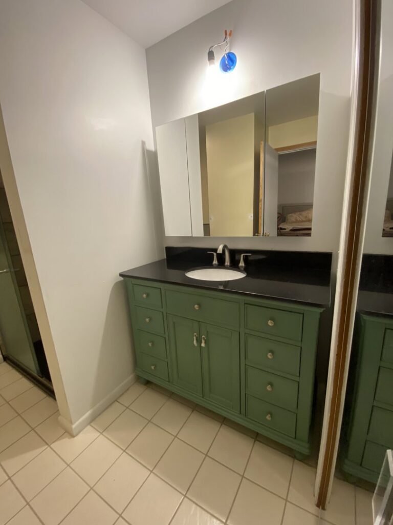 A newly installed green bathroom vanity with a black countertop, sink, and medicine cabinet by Coastal Home Improvements in Greenwood, DE.