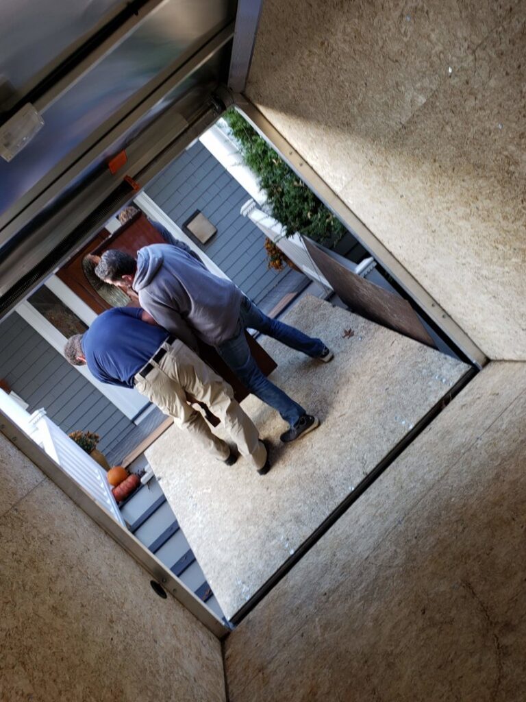 Green Clover team members loading a large piece of furniture into a junk removal trailer in Quincy, MA.