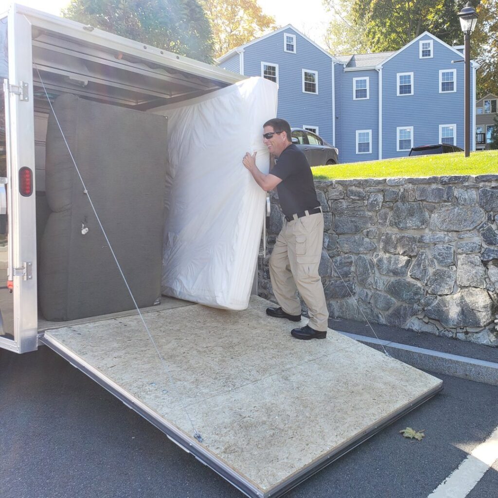 A Green Clover team member loading a mattress into a junk removal trailer in Quincy, MA.