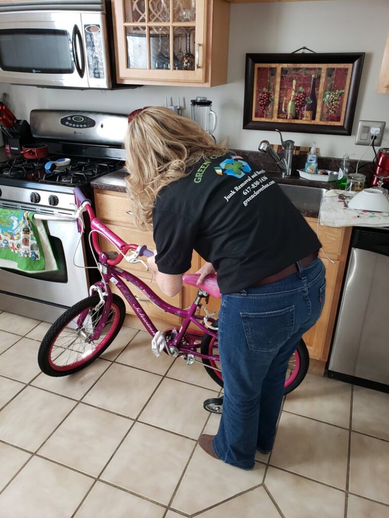 A Green Clover team member preparing a pink bicycle for removal from a kitchen in Quincy, MA.
