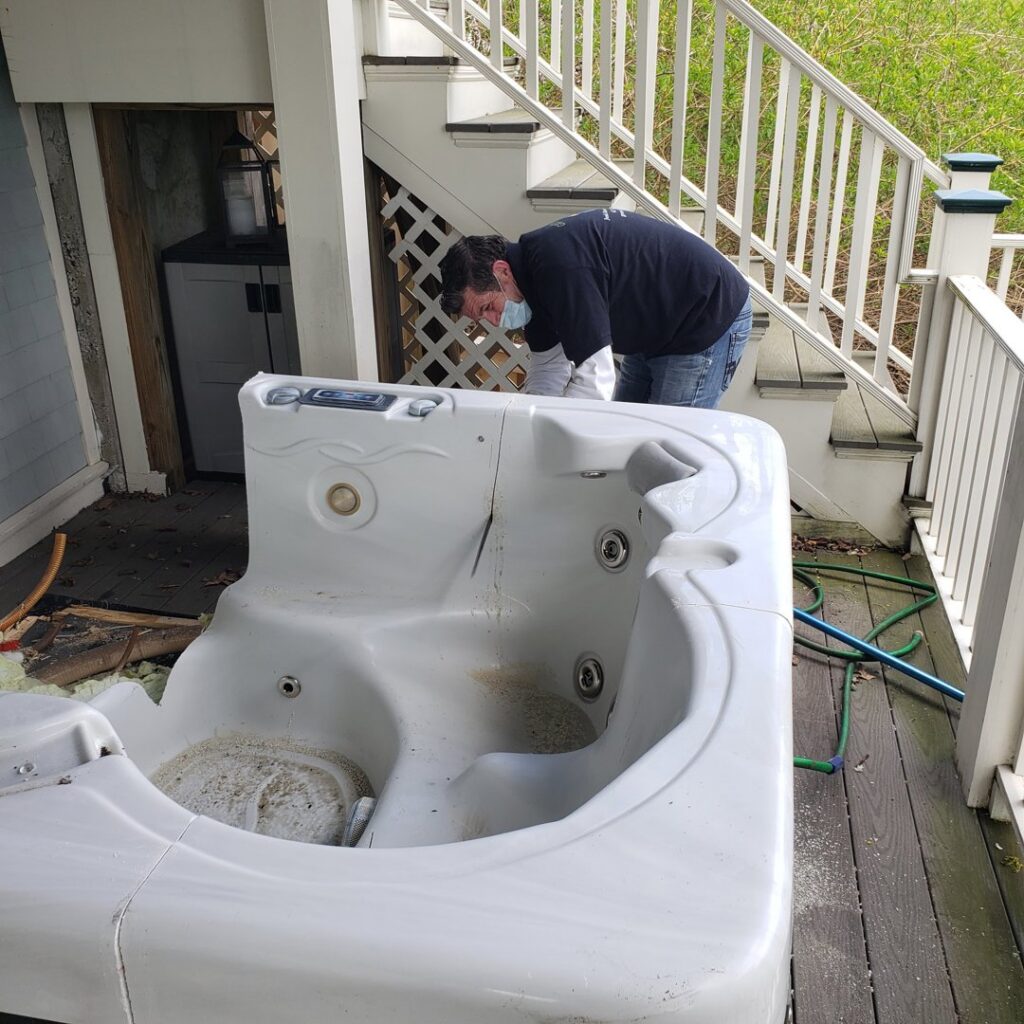 A Green Clover team member working on removing a large, old hot tub from a deck in Quincy, MA.