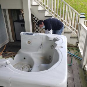 A Green Clover team member working on removing a large, old hot tub from a deck in Quincy, MA.