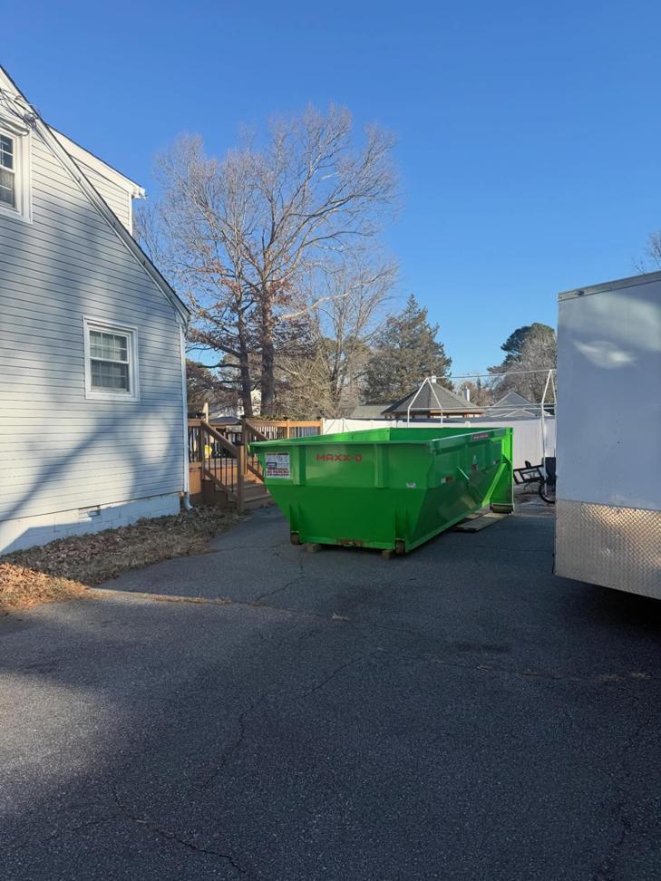 A bright green dumpster delivered to a residential driveway by Great Bridge Bins, LLC in Chesapeake, VA.