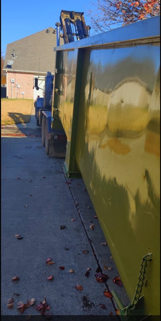 A green dumpster from FJD Waste Disposal and Recycling LLC placed on a residential driveway for general junk removal in Dallas, TX.