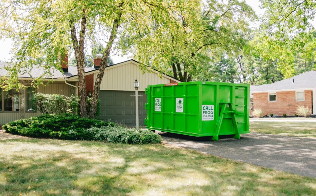 A green Frog Hauling dumpster placed in a residential driveway for junk removal in Columbus, OH.