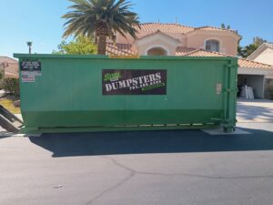 A green dumpster from Junk Control placed in a residential driveway for junk removal in Henderson, NV.
