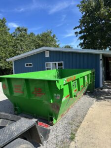 A green dumpster from American Dumpster Rentals placed in front of a residential building in Morrilton, AR.