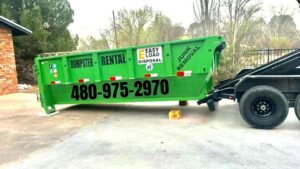 A green dumpster trailer being delivered or picked up by Easy Load Disposal El Paso for junk removal in El Paso, TX.