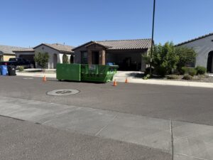 A green dumpster trailer from Easy Load Disposal El Paso parked on a residential street for a junk removal project in El Paso, TX.