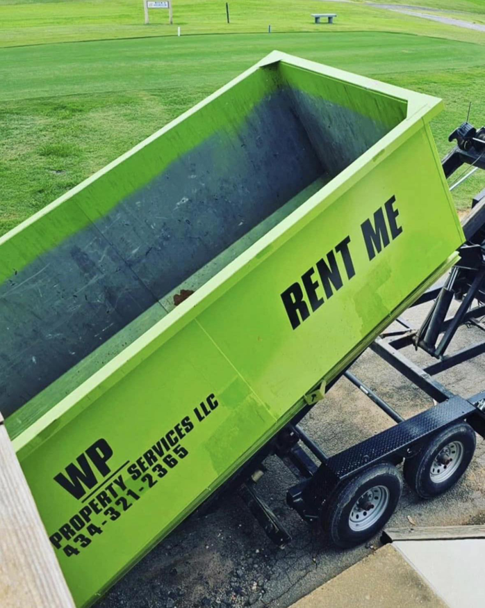 A bright green dumpster being tilted on a trailer by Wood Property Services & Dumpster Rental LLC in Wilmington, NC.