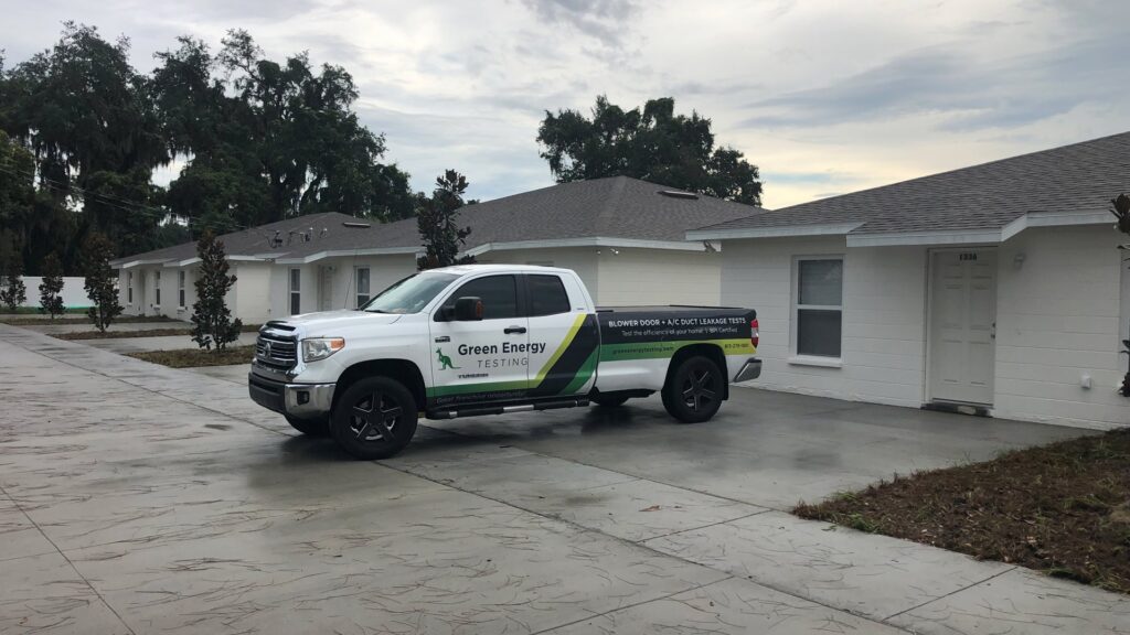 A Green Energy Testing branded truck parked at a new home construction site in Tampa, FL, ready for energy tests.