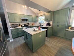 A stylish green kitchen remodel featuring an island and new appliances by Benjamin Design - Build in Fishers, IN.