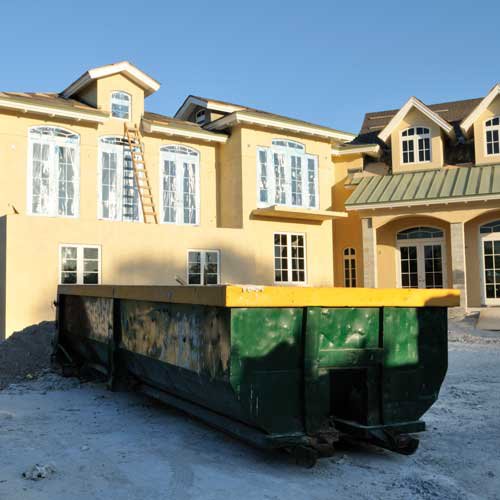 A green and yellow roll-off dumpster at a construction site for junk removal services by RBS Sanitation Inc. in Tea, SD.
