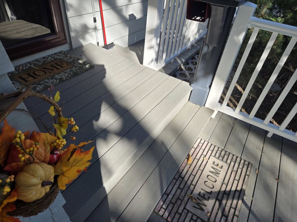 A modern grey composite entry deck with white railings, a professional installation by Great Falls Deck & Carpentry in Great Falls, MT.