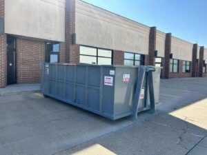 A grey dumpster from 515 Dumpsters placed in a commercial parking lot in West Des Moines, IA.