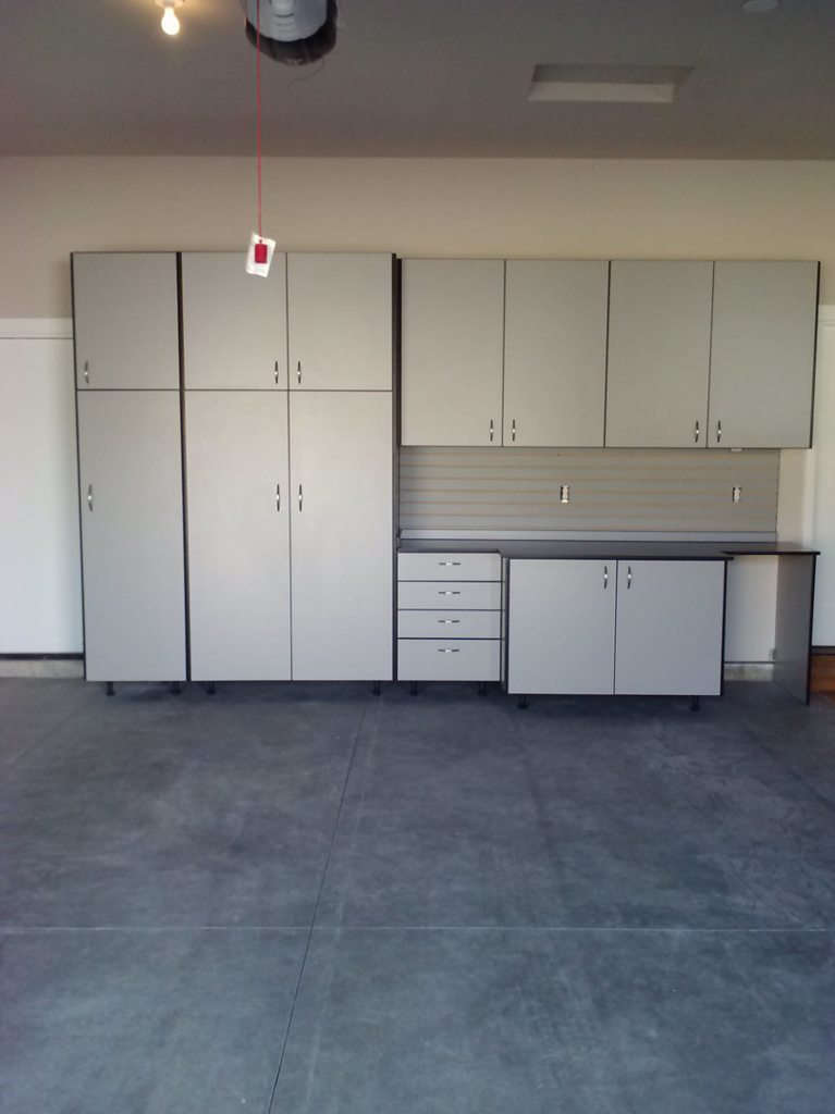 Grey garage cabinets with black trim, a workbench, drawers, and slatwall installed by NW Garage Cabinet Company in Ridgefield, WA.