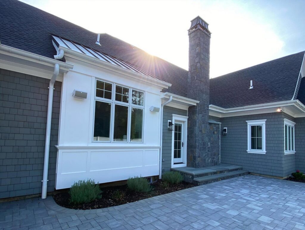 A house featuring new grey shingle siding and a stone chimney, a completed exterior by Ideal Siding Richmond, VA.