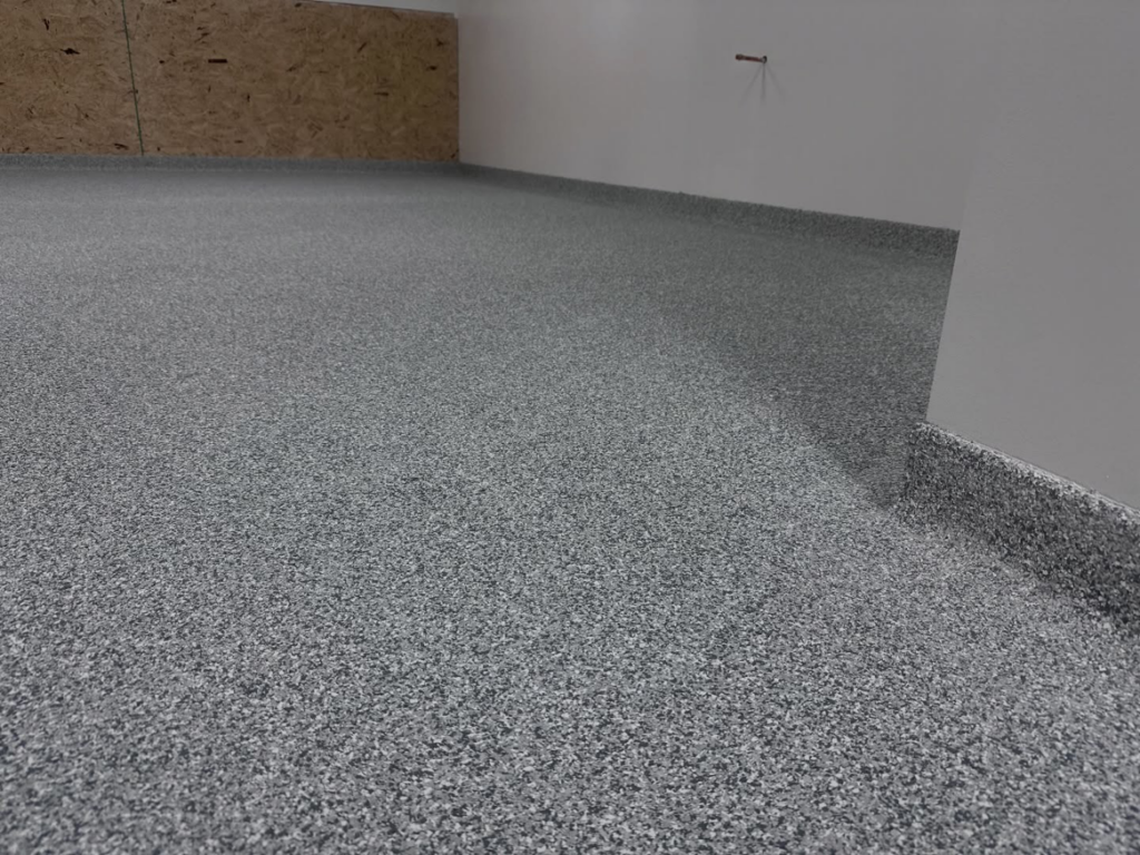 A close-up view of a durable grey speckled epoxy floor coating in a garage by 812 Concrete Coatings in Evansville, IN.