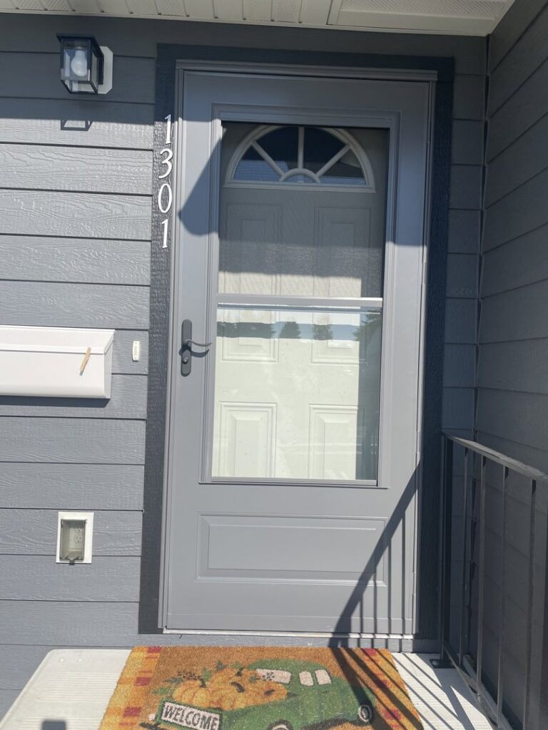 A newly installed grey storm door on a home, a professional handyman service provided by Great Falls Deck & Carpentry in Great Falls, MT.