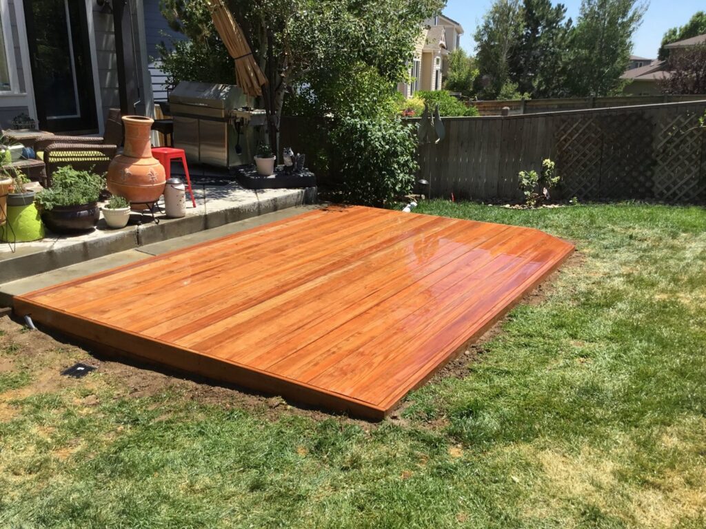 A newly installed ground-level wooden deck in a backyard by Lnk Deck & Remodels, LLC in Aurora, CO.