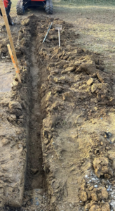 A long trench dug in the ground for excavation work by Tharp's Roofing & Construction in Owensboro, KY.