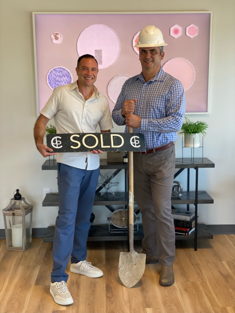 Two men, one in a hard hat with a shovel, celebrating a sold home project by Papino Homes in Plano, TX.