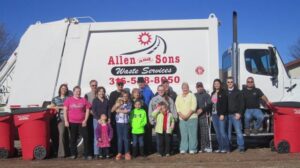 A group of employees and family members standing in front of a waste collection truck for Allen and Sons Waste Services in Wichita, KS.