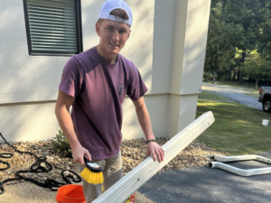 A handyman cleaning a section of gutter during maintenance by Profix Home Repair in Jonesboro, AR.