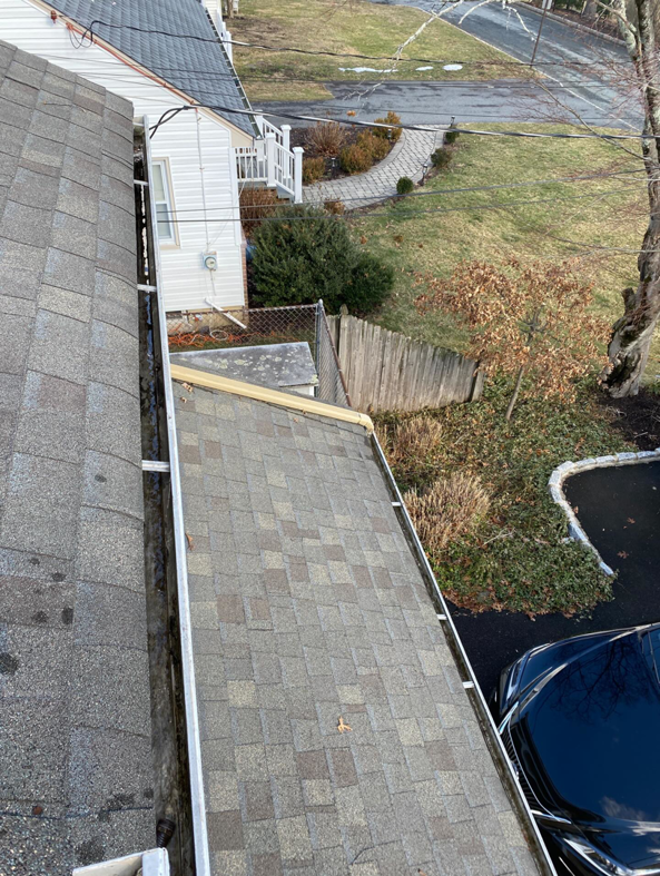 An aerial view from a roof showing a gutter with some debris, indicating a gutter inspection by DiEduardo Home Services LLC in Edison, NJ.