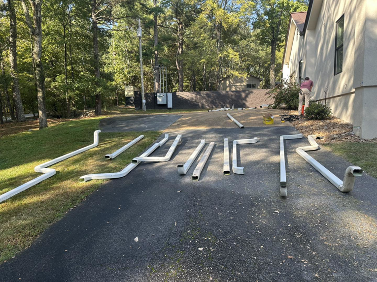 Sections of white gutters laid out on a driveway for installation by Profix Home Repair in Jonesboro, AR.