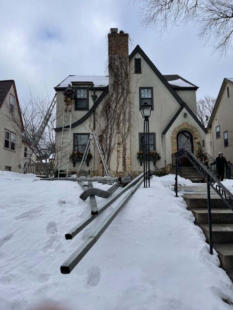 A handyman from Nordic Construction installing or repairing gutters on a house in Plymouth, MN.