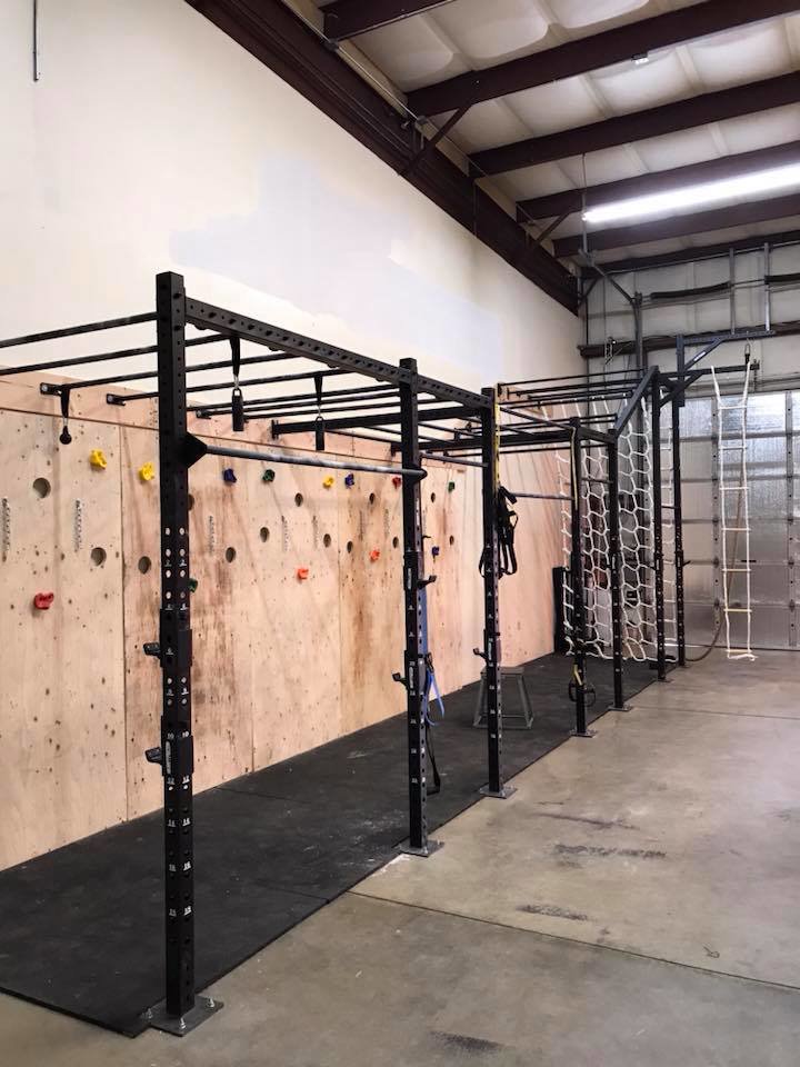 Interior view of a gym with a custom climbing wall and monkey bars installed by Fisher Construction, LLC in Selah, WA.