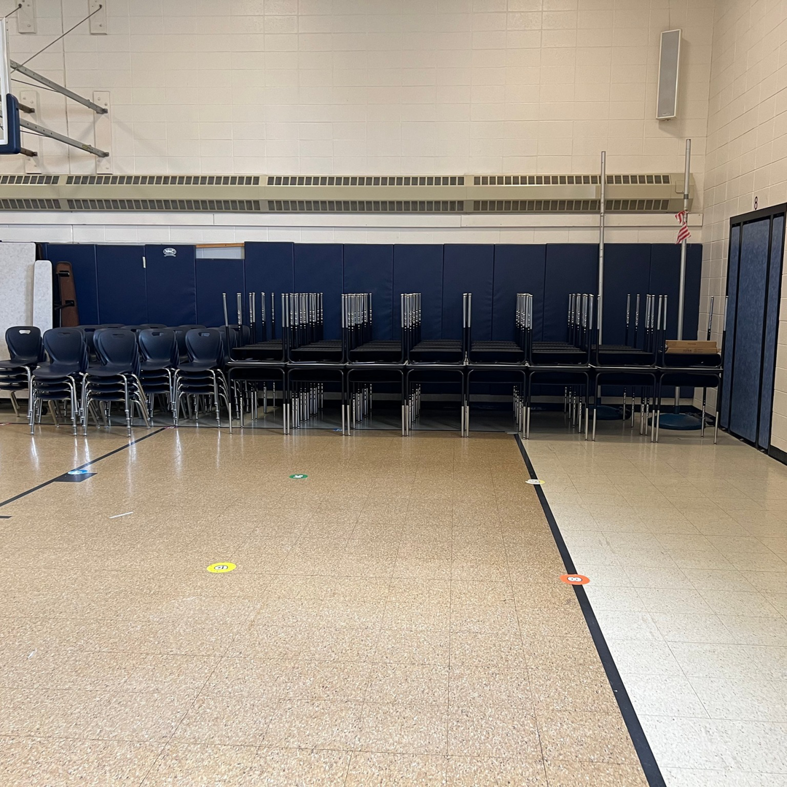 A school gymnasium with rows of chairs neatly stacked, a service provided by Jez Enterprises in Aurora, CO.