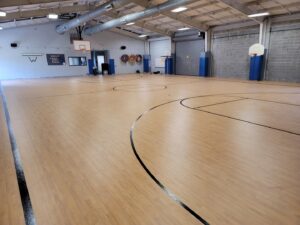 A spacious gymnasium with a newly installed basketball court floor and markings by Simply Construction in Las Vegas, NV.