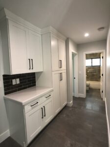 Custom hallway cabinetry with a dark subway tile backsplash leading to a bathroom, installed by Ignite Construction in Tempe, AZ.
