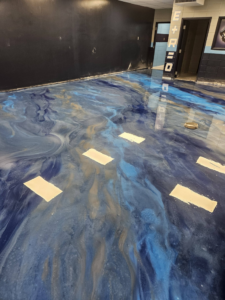 A long hallway with custom blue and gold epoxy flooring installed by New Age Decorative Concrete in Broussard, LA.