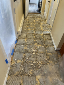 Hallway floor tile demolition in progress with debris by Main Street Handyman, LLC in Winter Garden, FL.