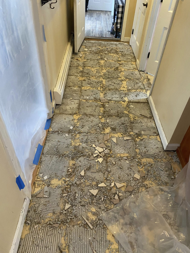 Hallway floor tile demolition in progress with debris by Main Street Handyman, LLC in Winter Garden, FL.