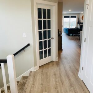 An interior hallway showcasing new flooring and a newly installed glass-paneled door by Clear Choice Handyman LLC in Woodbury, MN.