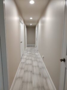A renovated hallway featuring new wood-look tile flooring and modern recessed lighting, installed by Devco Construction LLC in West Valley City, UT