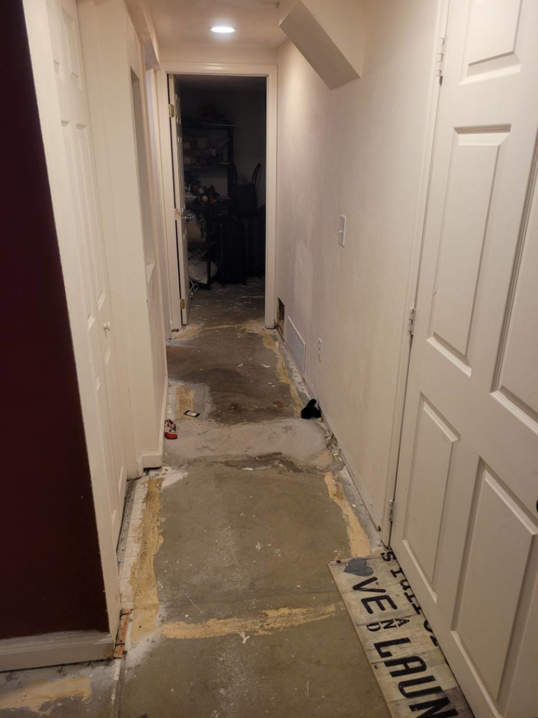 A hallway with subfloor exposed, showing a flooring replacement project by All In Remodeling Services LLC in Arvada, CO.