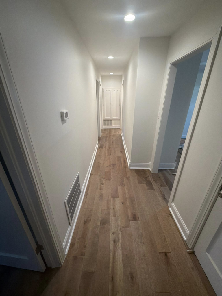 A newly renovated hallway featuring hardwood floor installation and fresh paint by GE Renovations LLC in Albertville, AL