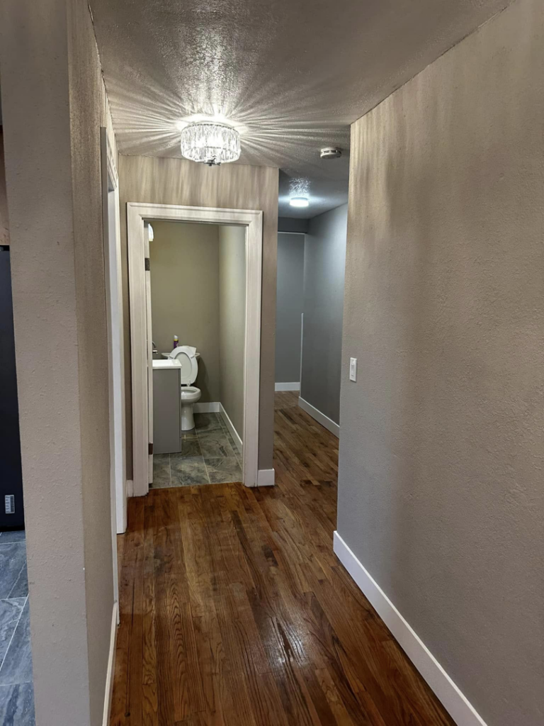 Newly remodeled hallway with hardwood floor, fresh paint, and modern light fixture by A to Z Remodeling llc in Gresham, OR.