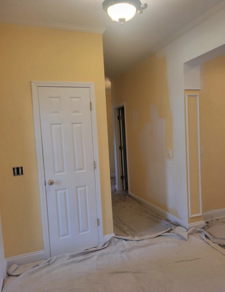 Interior hallway painting in progress with drop cloths on the floor by Carnelli Painting in Sumter, SC.