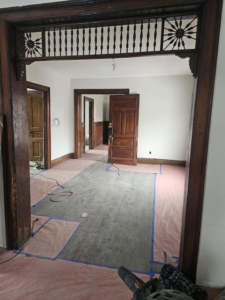 An interior hallway undergoing renovation with floor protection and exposed wiring, by Done Well Home Improvement LLC in Buffalo, NY.