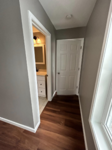 A newly renovated hallway with hardwood flooring and fresh paint by Rock Solid Construction in Rochester, NY