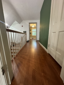 A long hallway featuring a beautifully refinished medium brown wood floor by SANDMAN WOOD FLOOR REFINISHING in Cleveland, OH.