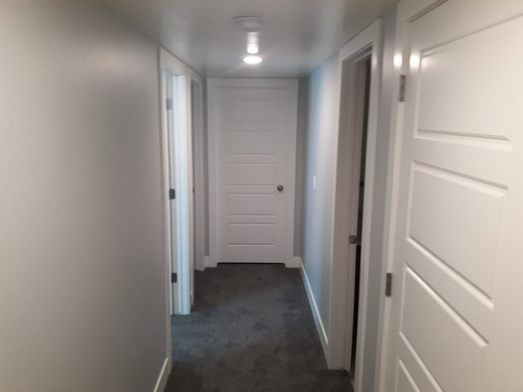 A freshly renovated hallway with new doors, paint, and carpet, completed by Eagle Rock Handyman Services in Caldwell, ID.